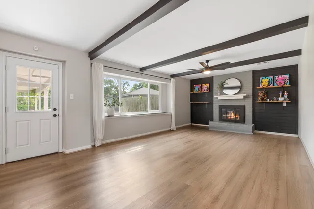an empty room with wooden floor fireplace and windows