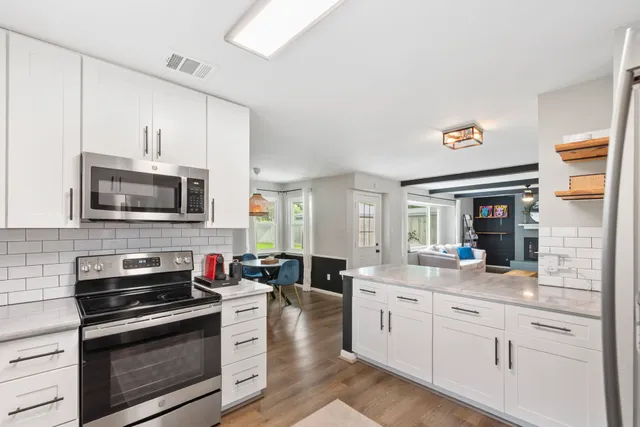 a kitchen with stainless steel appliances white cabinets and a stove top oven