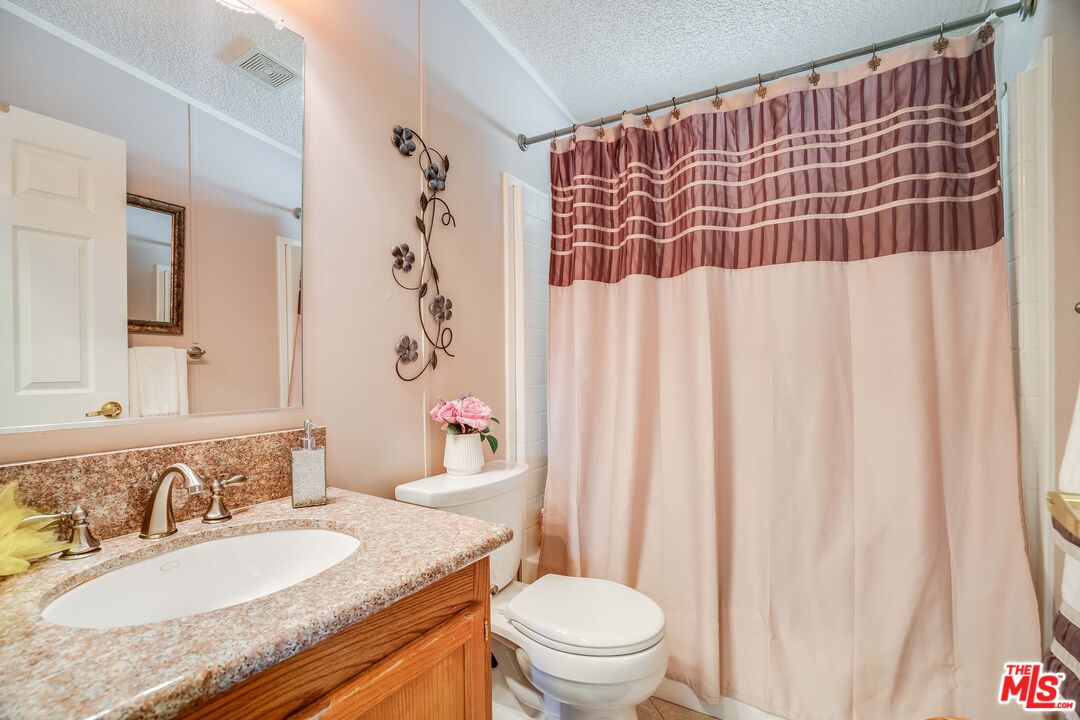 1111 Cherokee Topanga, CA 90290 - Photo 13 of 21 a bathroom with a granite countertop sink toilet a mirror and shower curtain