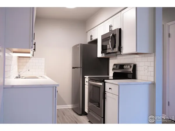 a kitchen with stainless steel appliances a sink a stove a microwave a refrigerator and cabinets