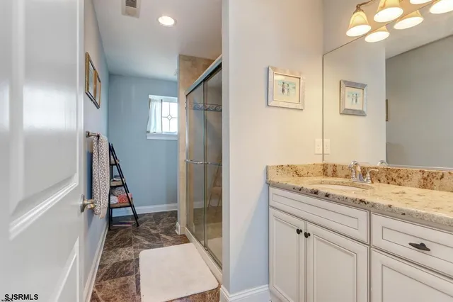 a en suite bathroom with a granite countertop sink and a mirror