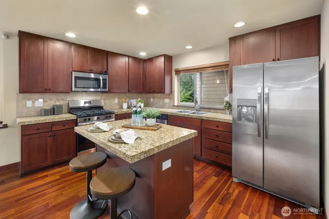 a kitchen with kitchen island granite countertop stainless steel appliances cabinets a sink and a center island