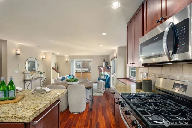 a kitchen with granite countertop lots of counter top space a sink stainless steel appliances and windows