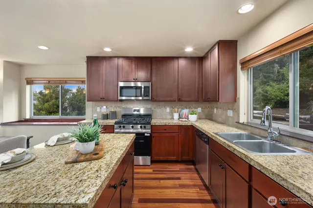 a kitchen with granite countertop kitchen island stainless steel appliances a sink stove and cabinets