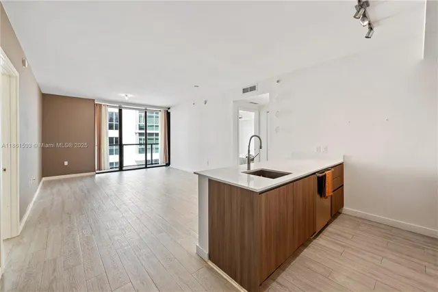 a kitchen with stainless steel appliances a sink and wooden floor