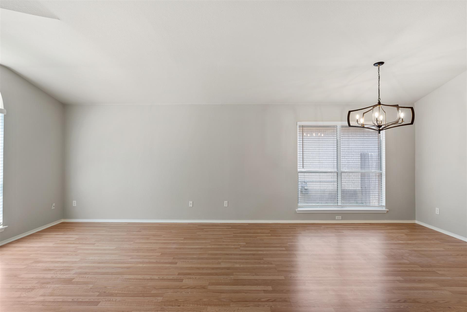 4725 Tello Path Austin, TX 78749 - Photo 11 of 34 A striking modern chandelier illuminates the spacious room with sleek hardwood floors and ample natural light.