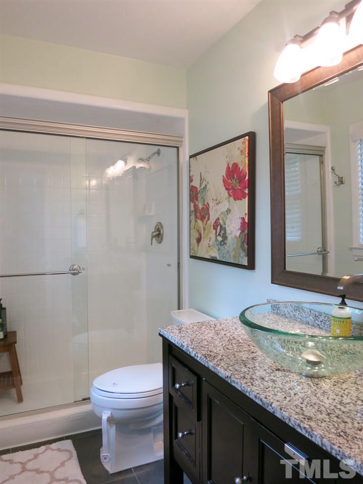 912 Hardimont Road Raleigh, NC 27609 - Photo 19 of 25 a bathroom with a granite countertop sink a toilet and a shower