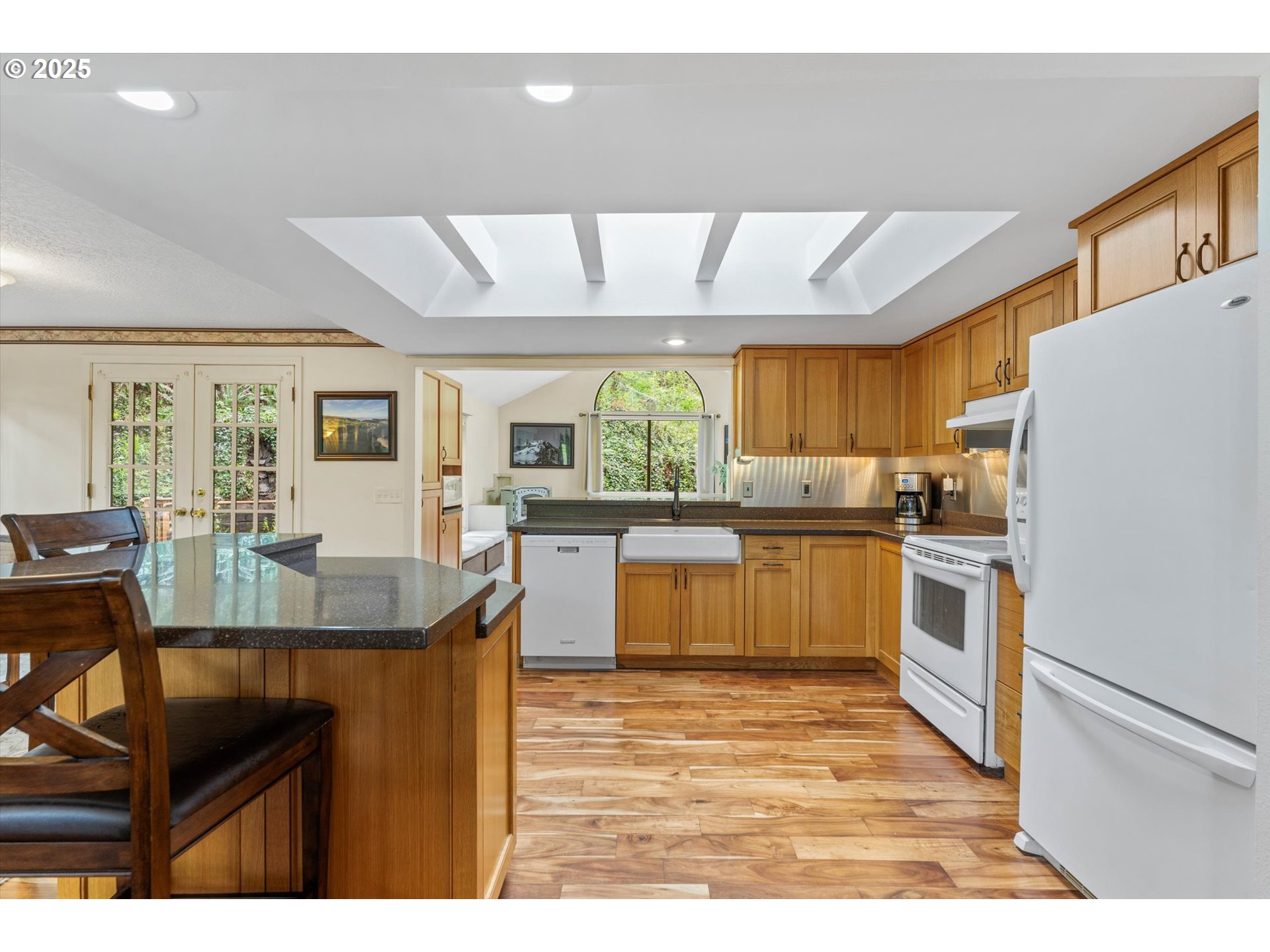 756 Southeast 27th Street Gresham, OR 97080 - Photo 10 of 46 a kitchen with stainless steel appliances kitchen island granite countertop a stove a sink dishwasher and white cabinets with wooden floor