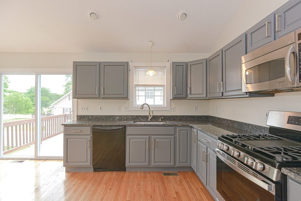 28 Aroostook Street Worcester, MA 01606 - Photo 5 of 40 a kitchen with stainless steel appliances granite countertop a stove a sink dishwasher and white cabinets with wooden floor