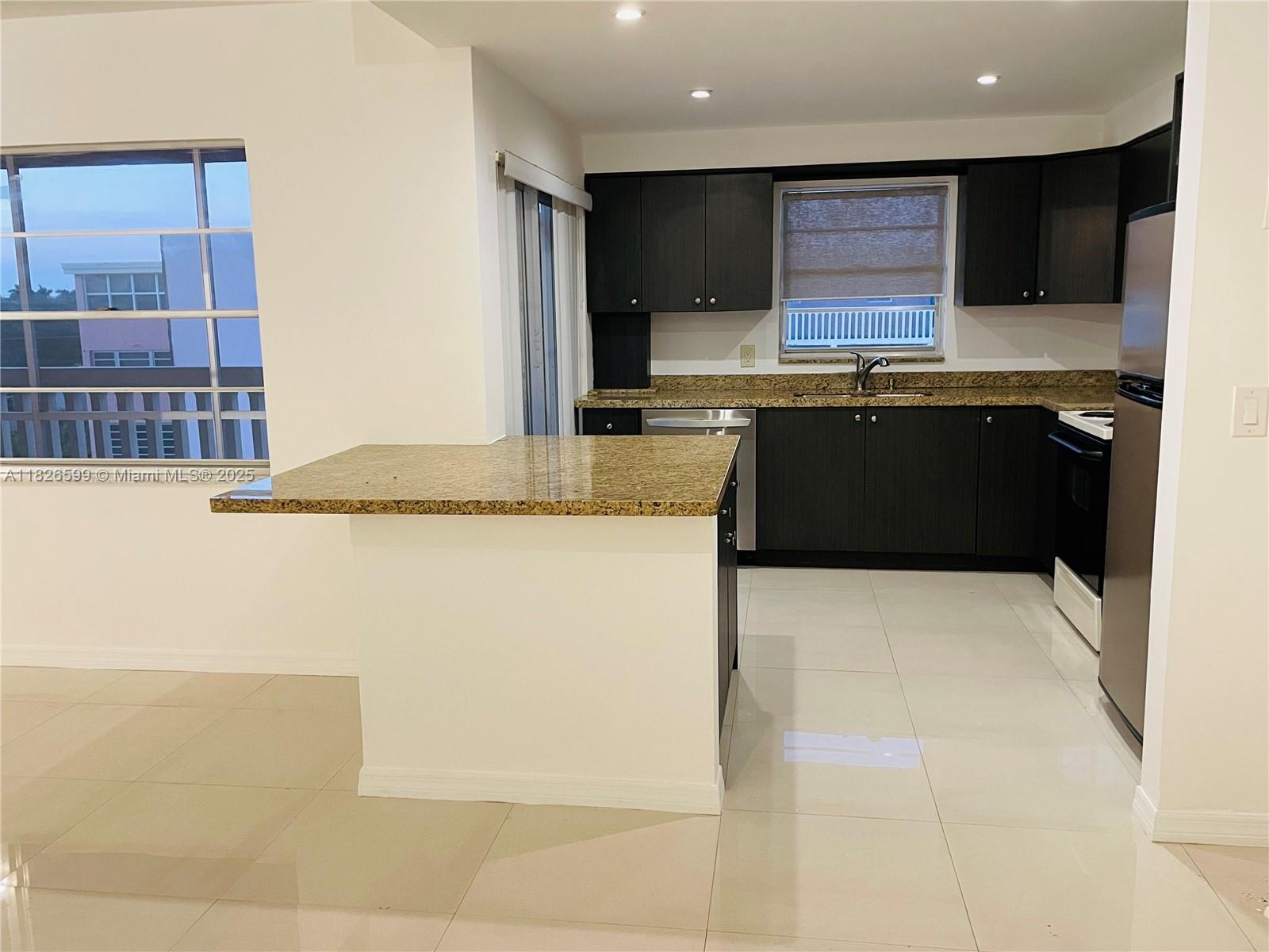 180 Northeast 12th Avenue, Unit 11E Hallandale Beach, FL 33009 - Photo 6 of 22 a kitchen with stainless steel appliances kitchen island granite countertop a refrigerator a stove and a sink