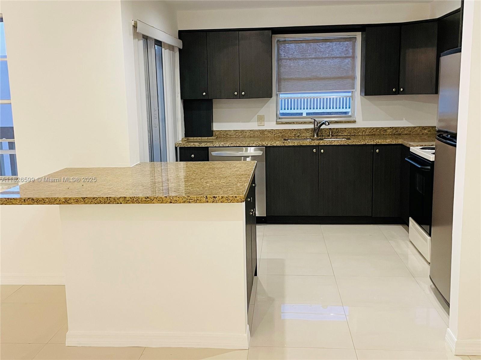 180 Northeast 12th Avenue, Unit 11E Hallandale Beach, FL 33009 - Photo 7 of 22 a kitchen with granite countertop a sink a stove and cabinets