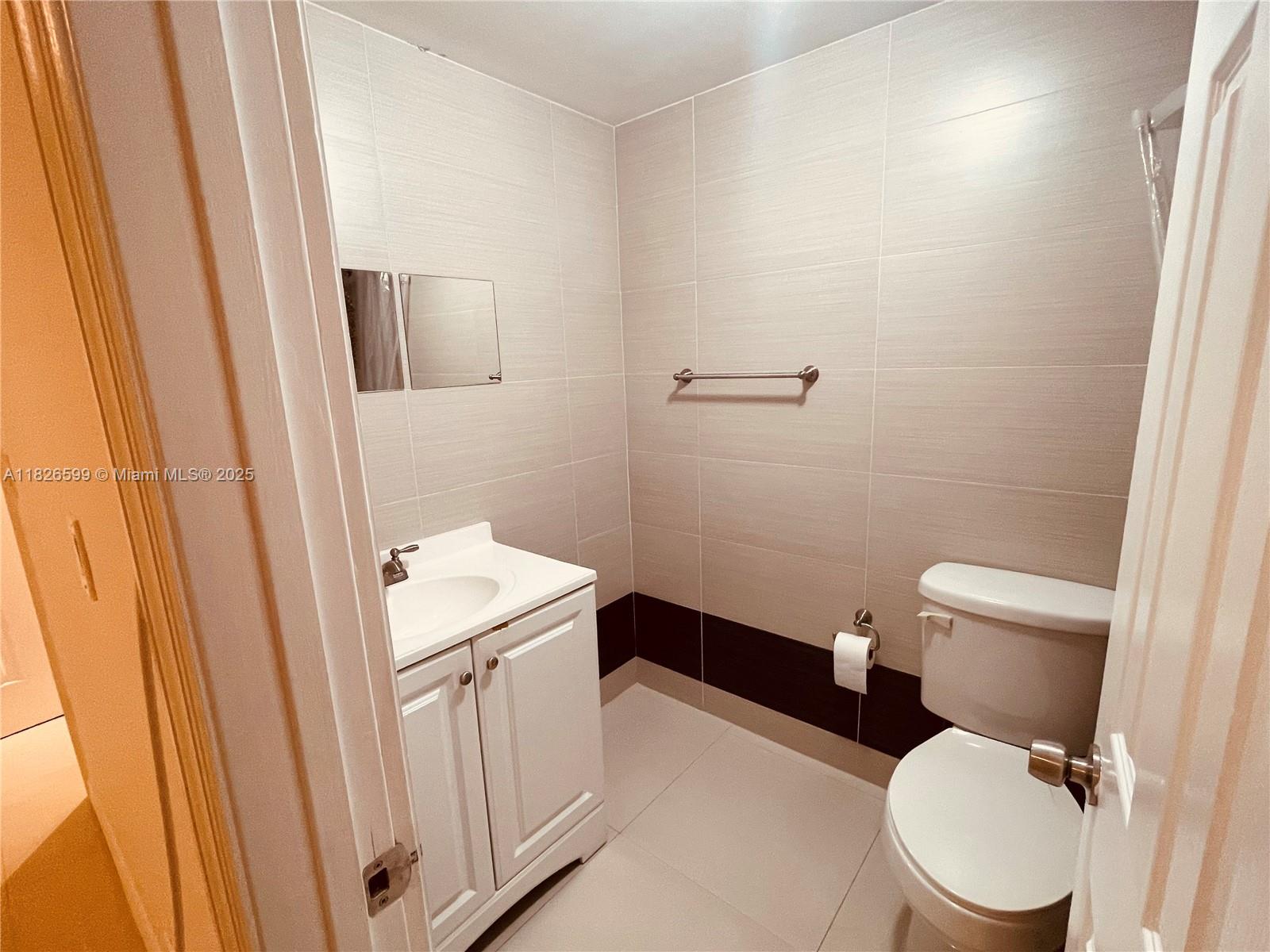 180 Northeast 12th Avenue, Unit 11E Hallandale Beach, FL 33009 - Photo 10 of 22 a bathroom with a toilet a sink and a mirror