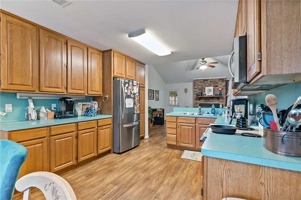 a kitchen with stainless steel appliances granite countertop a refrigerator a sink dishwasher and wooden cabinets with wooden floor