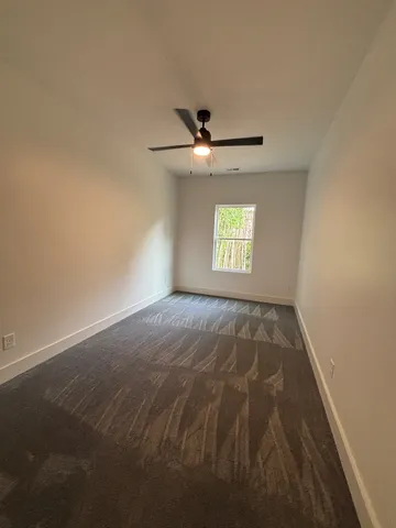 en empty room with windows and ceiling fan