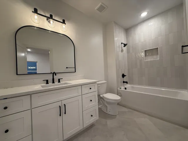 a spacious bathroom with a double vanity sink toilet mirror and bathtub