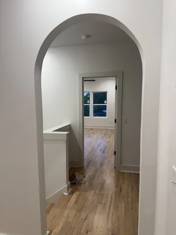 a view of a hallway with wooden floor and a bathroom