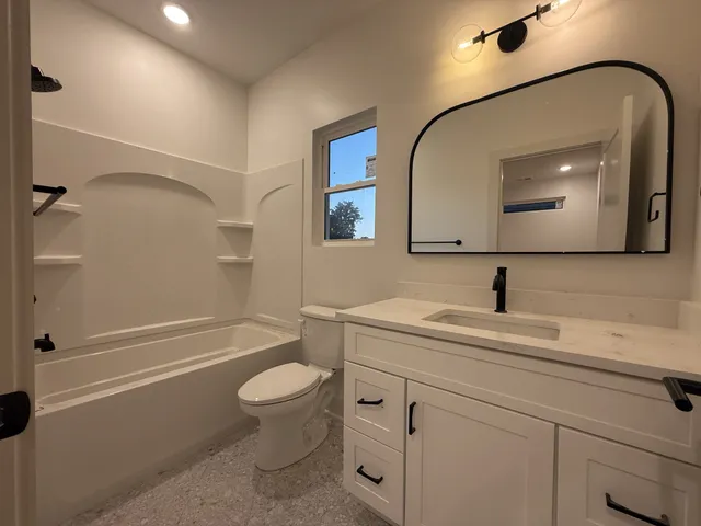 a bathroom with a toilet a sink a tub and a mirror