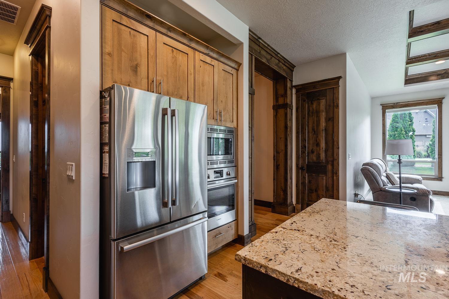 8077 Star Pass Ridge Road Nampa, ID 83686 - Photo 13 of 37 Spacious kitchen featuring an expansive granite island with undermount sink, stainless steel appliances, and wood-finish flooring