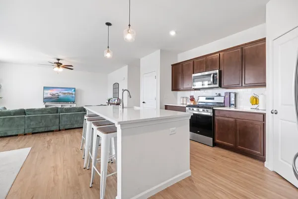 a kitchen with kitchen island stainless steel appliances a sink cabinets and wooden floor