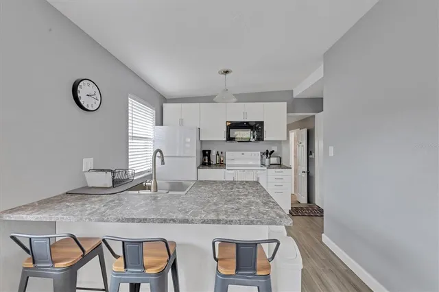 a kitchen with kitchen island granite countertop a table chairs microwave and cabinets