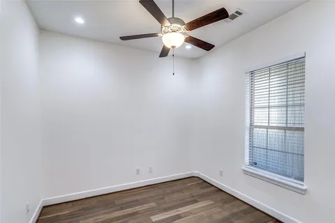 an empty room with a window and ceiling fan