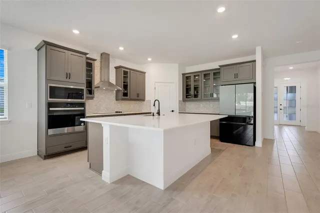a large white kitchen with stainless steel appliances kitchen island a large counter top and a sink