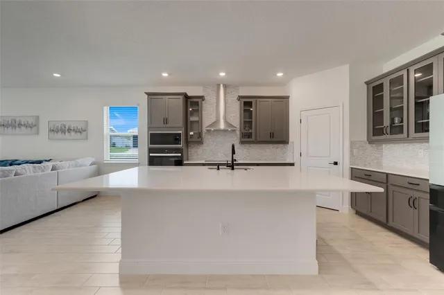 a large white kitchen with kitchen island a sink stainless steel appliances and cabinets