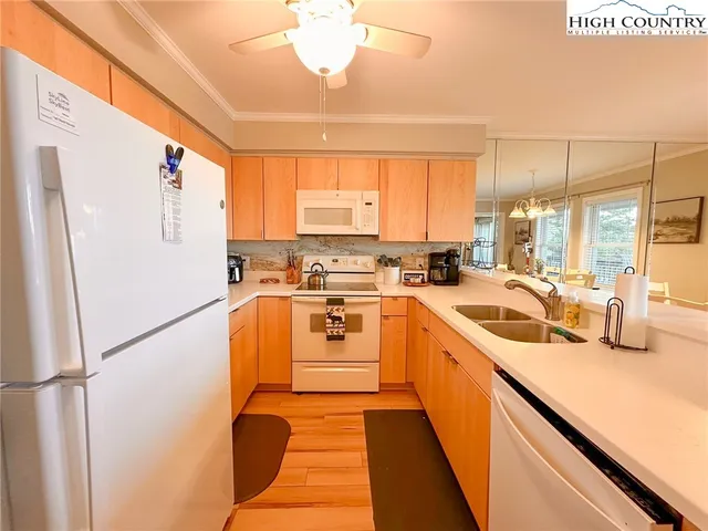 a kitchen with stainless steel appliances granite countertop a refrigerator a sink dishwasher a stove with white cabinets and wooden floor