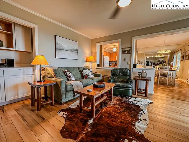 a living room with furniture a wooden floor and next to a window
