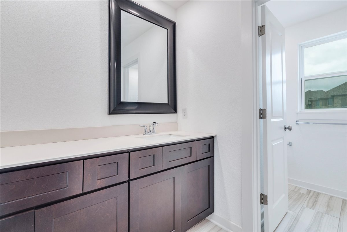 8008 Prairie Rye Drive Lago Vista, TX 78645 - Photo 25 of 40 Bathroom vanity featuring a dark wood-finish cabinet, white countertop, and an integrated sink with a chrome faucet