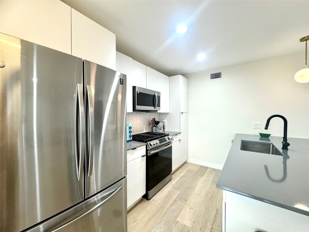 400 East 30th Street, Unit 101 Austin, TX 78705 - Photo 8 of 27 a kitchen with stainless steel appliances granite countertop a refrigerator a stove and a sink