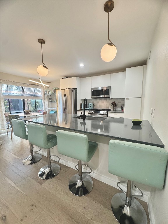 400 East 30th Street, Unit 101 Austin, TX 78705 - Photo 9 of 27 Kitchen with pendant lighting, white cabinetry, a kitchen bar, and appliances with stainless steel finishes