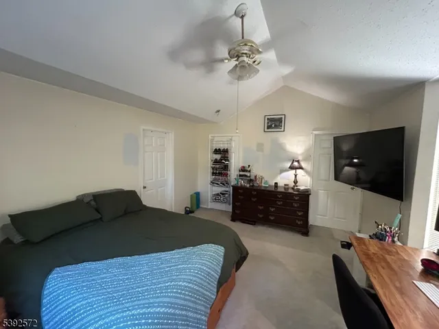a bedroom with a bed and a flat tv screen on dresser