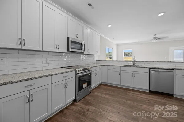 a kitchen with granite countertop white cabinets and white appliances