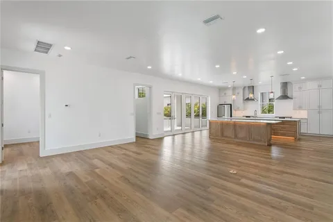a view of a kitchen with kitchen island white cabinetry and wooden floor