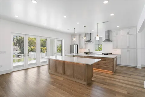 a large kitchen with stainless steel appliances a large counter top a stove and a refrigerator