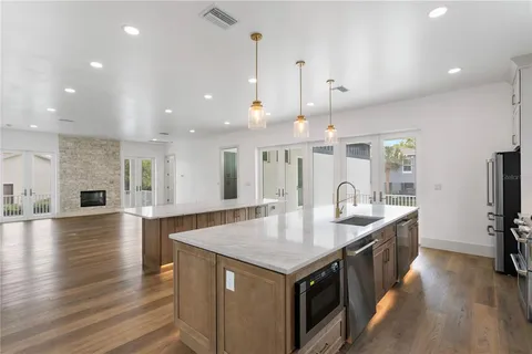 an empty room with wooden floor and kitchen view
