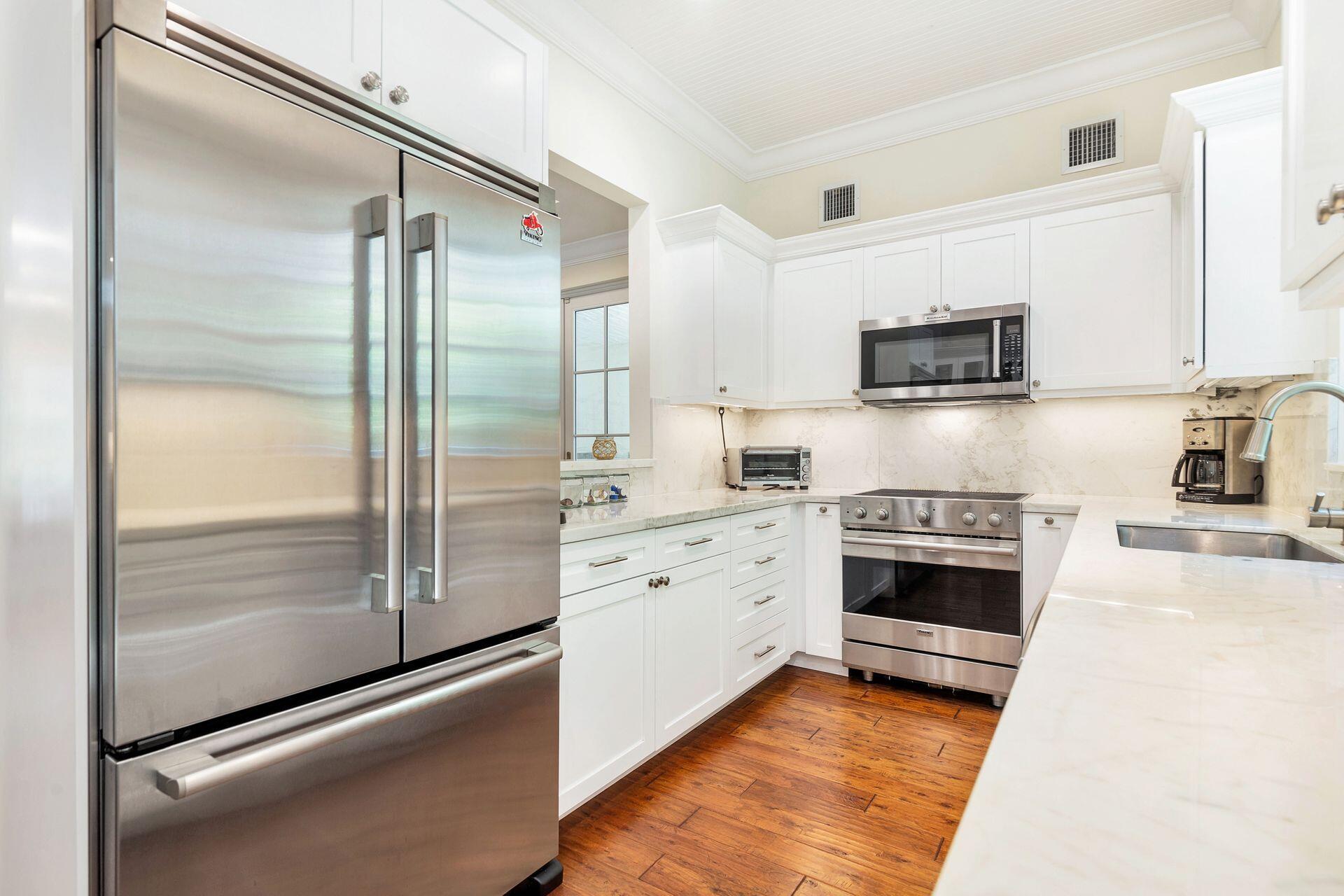 135 Root Trail, Unit A Palm Beach, FL 33480 - Photo 12 of 25 a kitchen with stainless steel appliances a refrigerator sink and stove