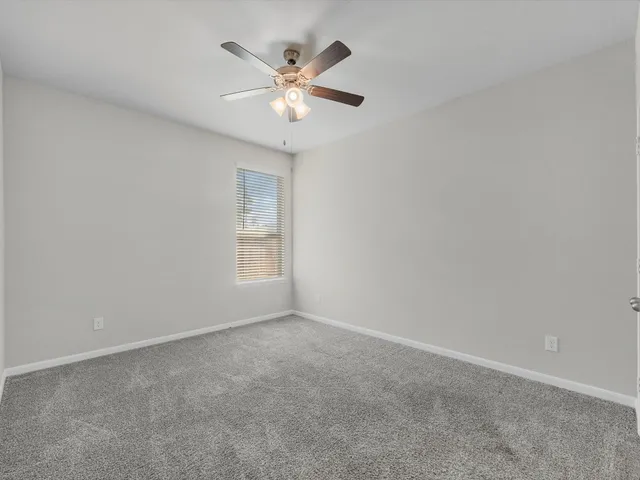 an empty room with a chandelier fan and windows