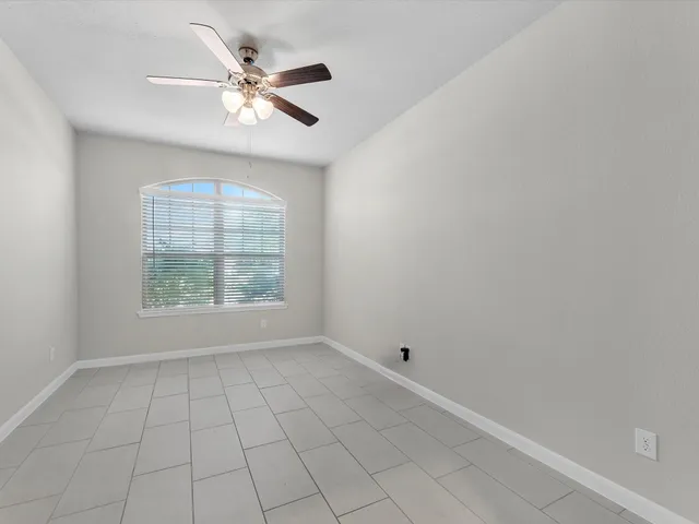 an empty room with windows and ceiling fan