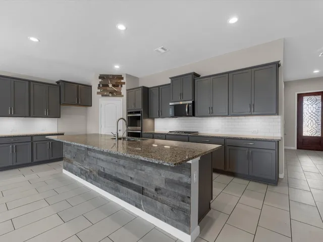 a large kitchen with granite countertop a sink a counter top space appliances and cabinets