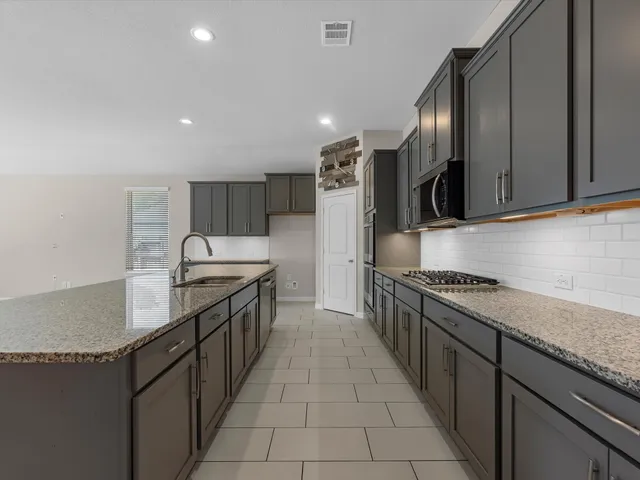 a kitchen with stainless steel appliances granite countertop a sink a stove and a refrigerator