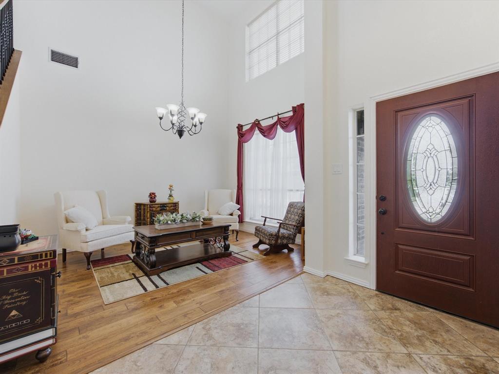 4008 Falcon Ridge Drive Haltom City, TX 76137 - Photo 4 of 40 Two-story foyer featuring a decorative glass panel front door, high ceilings, a wrought iron chandelier, wood-finish flooring, and a staircase with an open railing