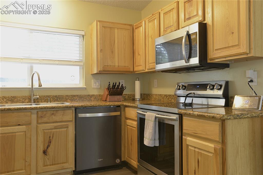 575 Blossom Field Road Fountain, CO 80817 - Photo 9 of 24 a kitchen with stainless steel appliances granite countertop a sink stove and cabinets