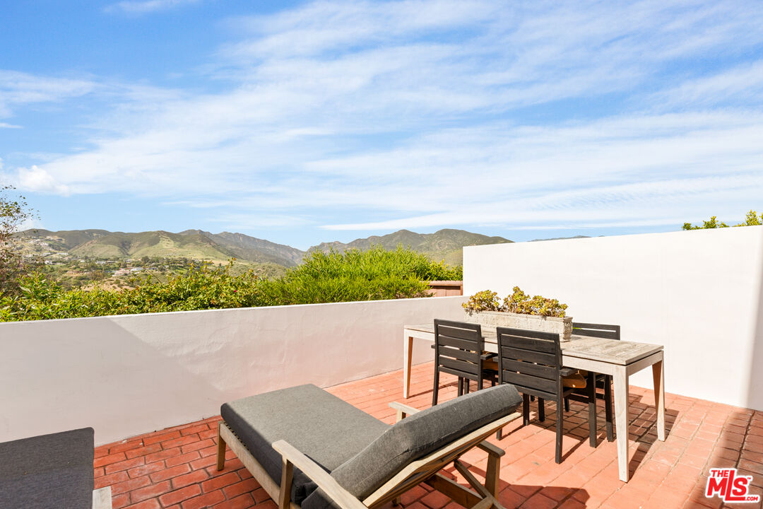 29221 Heathercliff Road, Unit 13 Malibu, CA 90265 - Photo 21 of 43 a view of a terrace with a table and chairs
