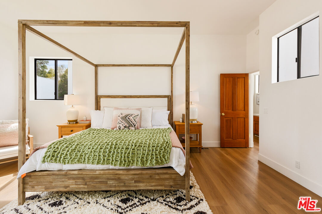 29221 Heathercliff Road, Unit 13 Malibu, CA 90265 - Photo 4 of 43 a bedroom with a large bed and wooden floor