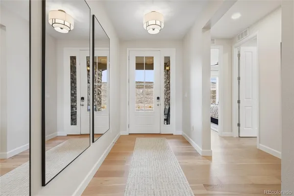 a view of a hallway with wooden floor and a bathroom