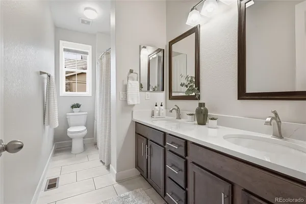 a spacious bathroom with a granite countertop sink toilet and mirror