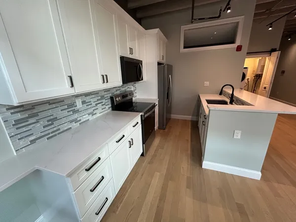 a kitchen with stainless steel appliances a stove microwave and sink