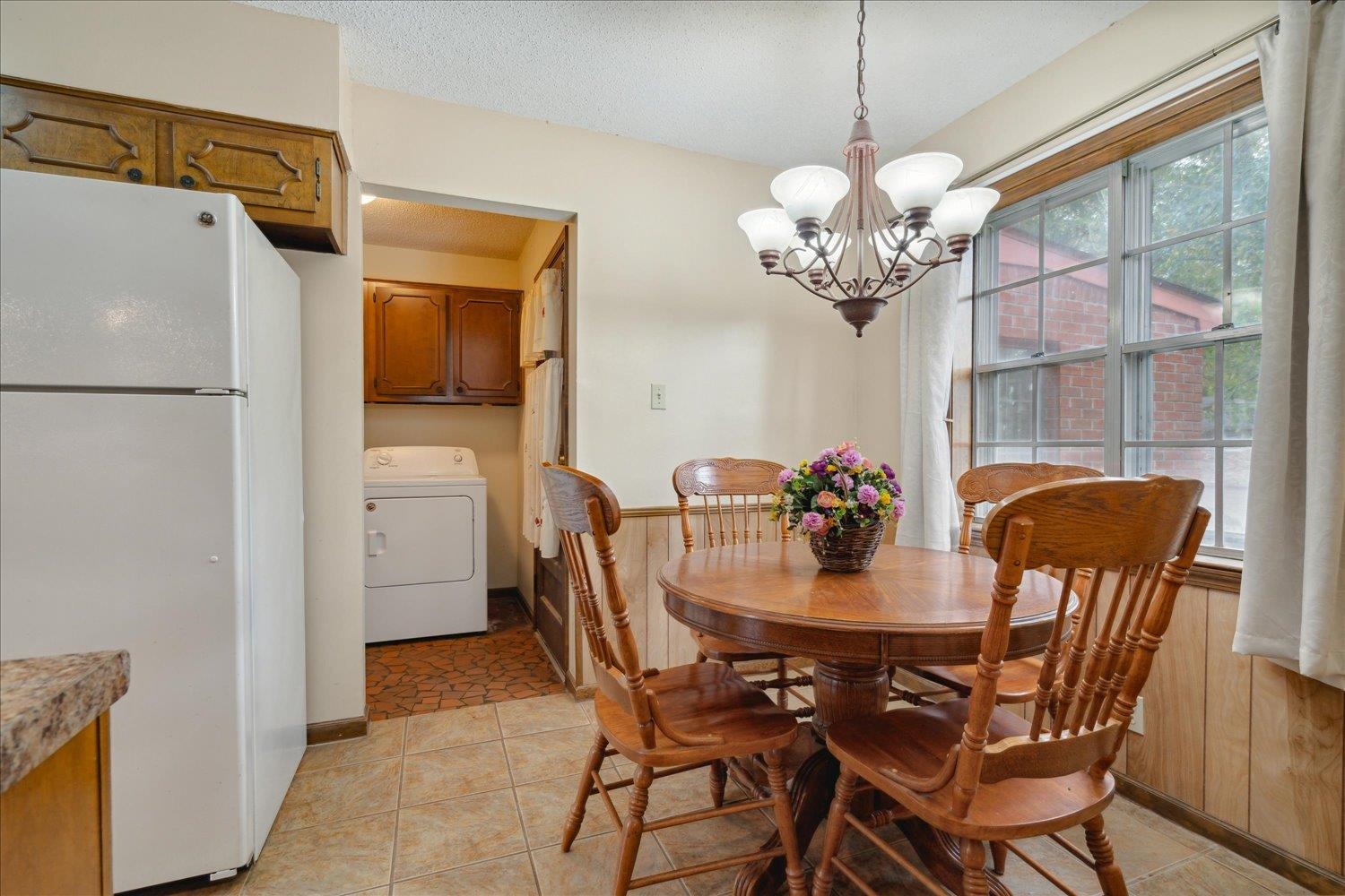 4839 Yale Road Memphis, TN 38128 - Photo 11 of 27 Dining space featuring washer / dryer, a textured ceiling, an inviting chandelier, and light tile patterned flooring